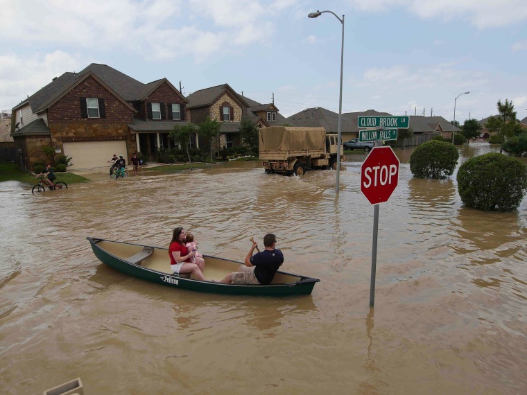 Image: A woman holds a baby in a canoe as Texas Guardsmen arrive to assist after flooding in Brookshire