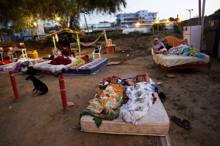 Image: People share a mattress as they sleep outside their collapsed homes