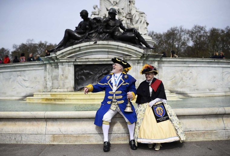 Image: Town Criers dressed in their traditional costumes watch the Changing of the Guard ceremony outside Buckingham Palace in London