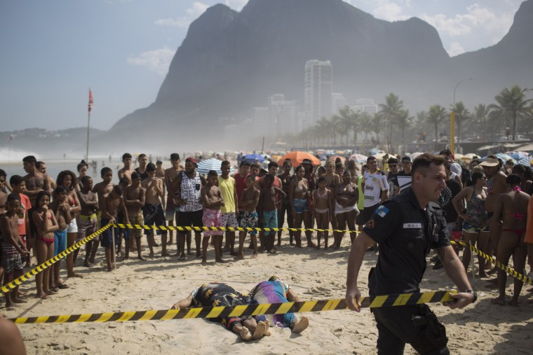 Image: A police officer tapes off the area around two people who were killed when a bike lane collapsed in Rio de Janeiro