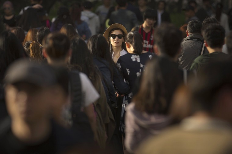 Image: A woman crosses a street at a busy intersection in central Beijing