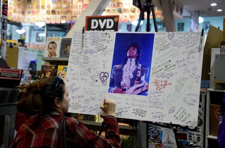 Image: A fan writes a message at a makeshift memorial at Amoeba Records in Hollywood, California