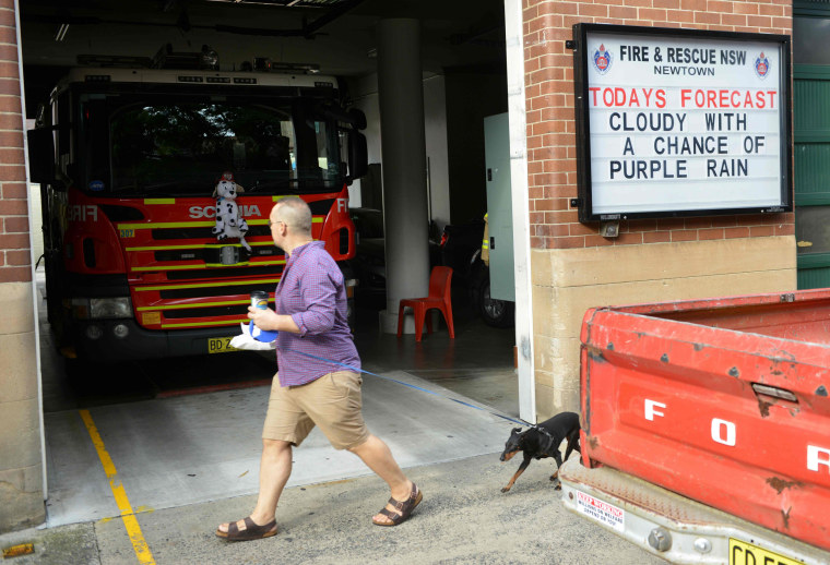 Image: A pedestrian walks past a fire station in Sydney with a tribute message displayed