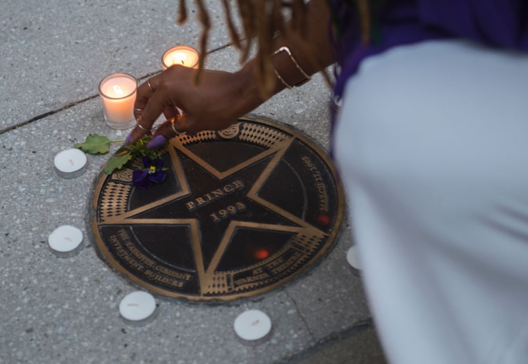 Image: A woman lights candles in remembrance to Prince around his star at the Warner Theater in Washington, D.C.