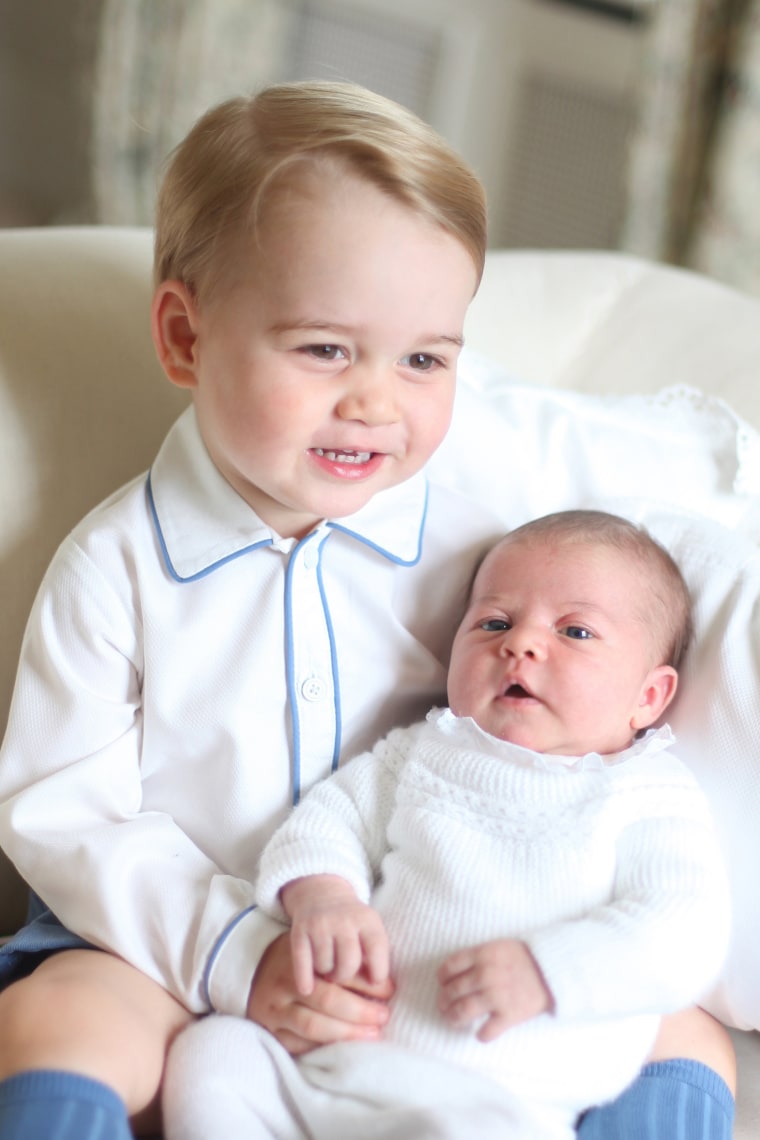 Prince George holding Princess Charlotte
