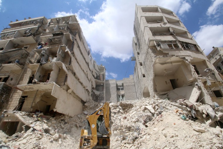 Image: A front loader operates at a site hit by airstrikes in the rebel held area of al-Sukari district of Aleppo