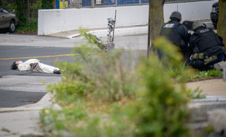 Image: A man, claiming to have a bomb, lies in the street outside of the Fox45 television station, which was evacuated due to a bomb threat, in Baltimore
