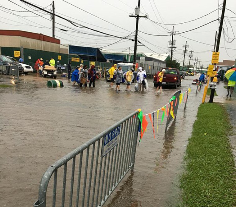 People walk through a flooded street at the New Orleans JazzFest on April 30.