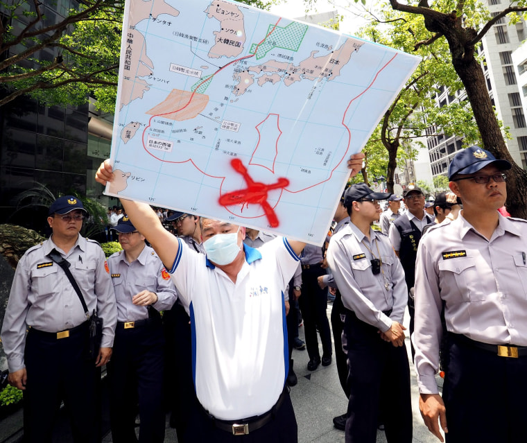 Image: A fisherman holding map showing location of Image: Map showing Okinotori in Taipei on April 27