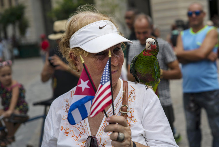 Image: A cruise passenger poses for a photo with a parrot in Havana