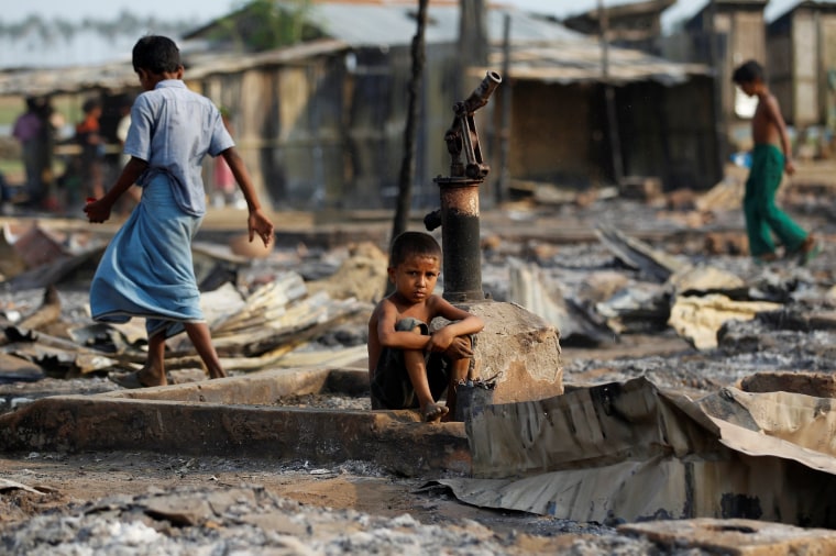 Image: A boy sit in a burnt area after fire destroyed shelters at a camp for internally displaced Rohingya Muslims in the western Rakhine State near Sittwe