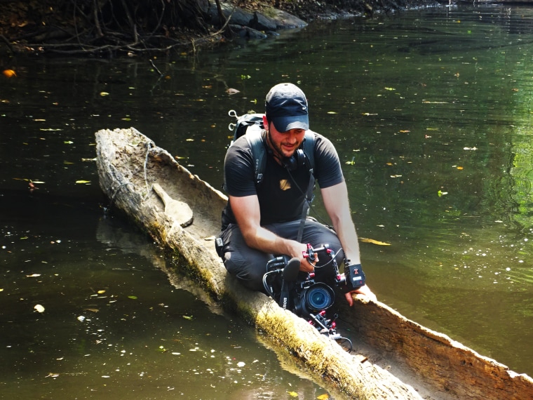 A crew member works to get the right shot inside a canoe made out of the hollow of a tree in the tropical Bili forest in the heart of the Congo.