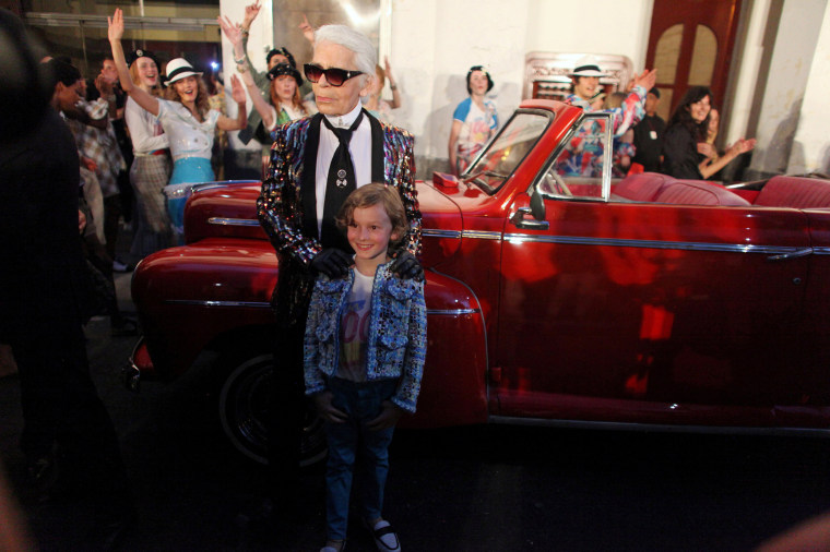 Image: Chanel's head designer and creative director Karl Lagerfeld poses with a model after a fashion show of his latest inter-seasonal Cruise collection, at the Paseo del Prado street in Havana, Cuba