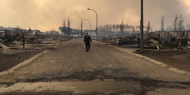 Image: A Mountie surveys the damage on a street in Fort McMurray.