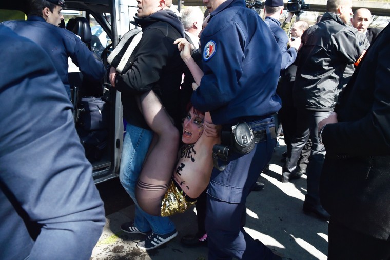 Image: French police officers detain a topless Femen activist during a protest