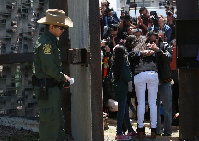 Image: A family embraces at the U.S.-Mexico Border fence