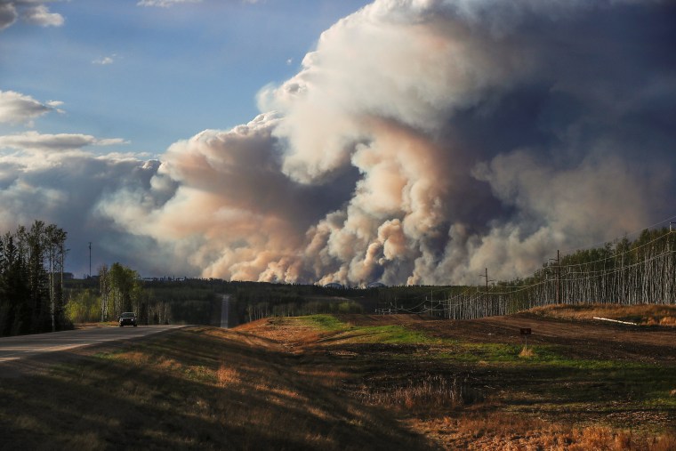 Image: Smoke billows from the Fort McMurray wildfires as a truck drives down the highway in Kinosis