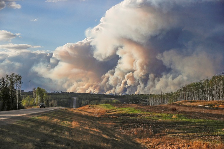 Image: Smoke billows from the Fort McMurray wildfires as a truck drives down the highway in Kinosis