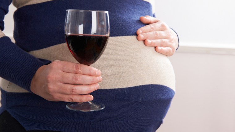 Pregnant woman drinking glass of wine