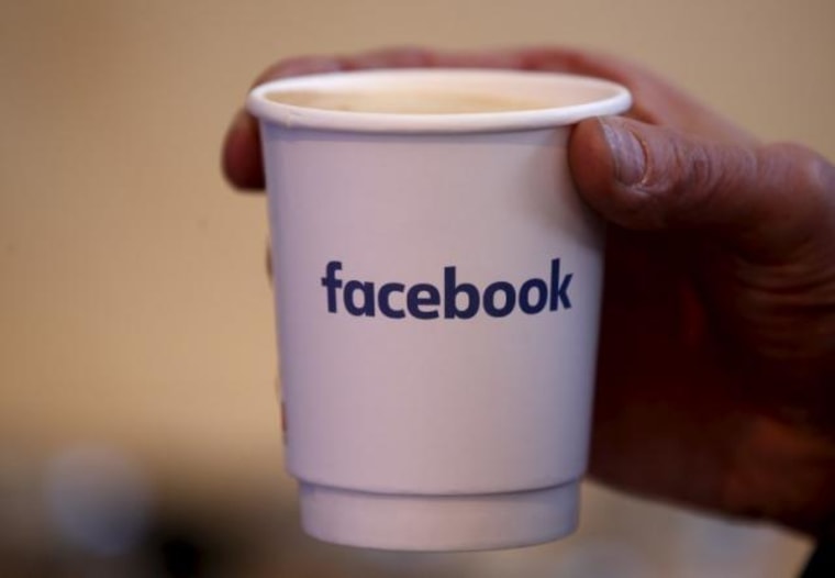 A journalist holds a cups with the Facebook logo at the new Facebook Innovation Hub during a preview media tour in Berlin