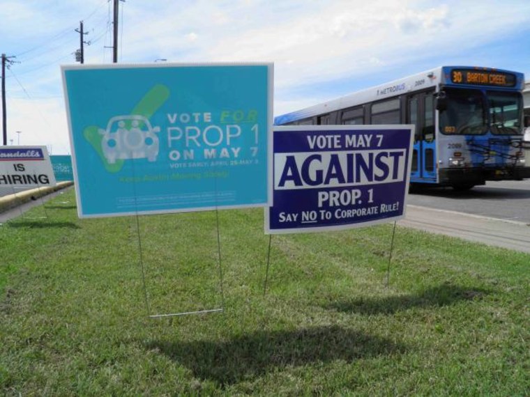 Campaign signs concerning a municipal vote over fingerprint requirements for ride-hailing companies such as Uber and Lyft are seen along a roadway in Austin