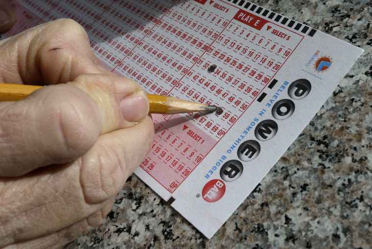Image: A lottery player fills out numbers on a powerball form in Oakland, Calif.