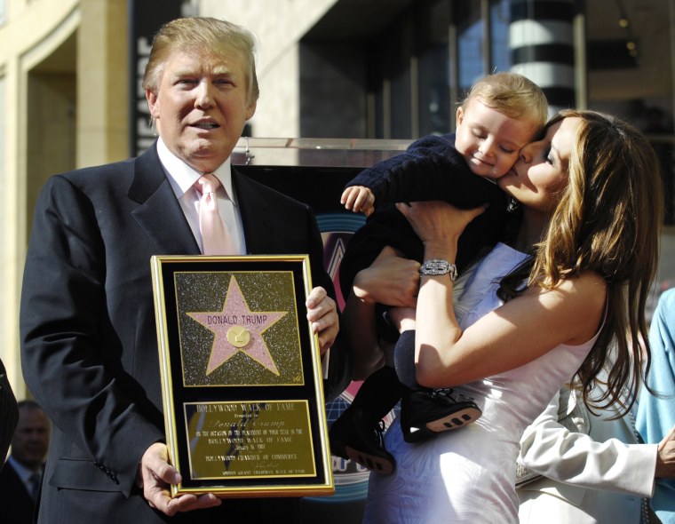 Image: Donald Trump holds a replica of his star on the Hollywood Walk of Fame as his wife Melania holds their son Barron in Los Angeles
