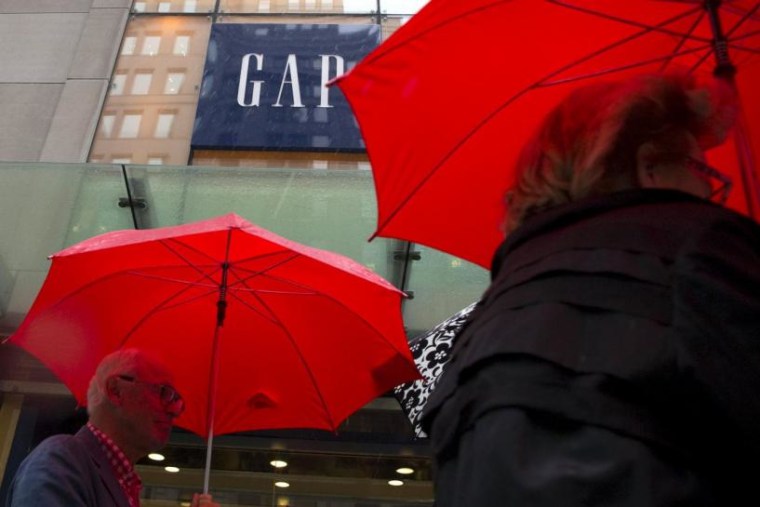 People carrying umbrellas pass by a Gap store on 5th avenue in midtown Manhattan in New York
