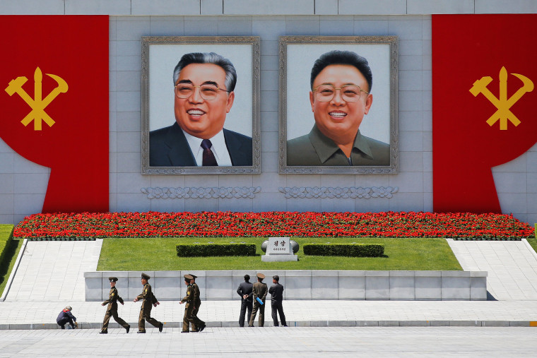 Image: People stand in front of pictures of former North Korean leaders Kim Il Sung and Kim Jong Il at the main Kim Il Sung square in central Pyongyang