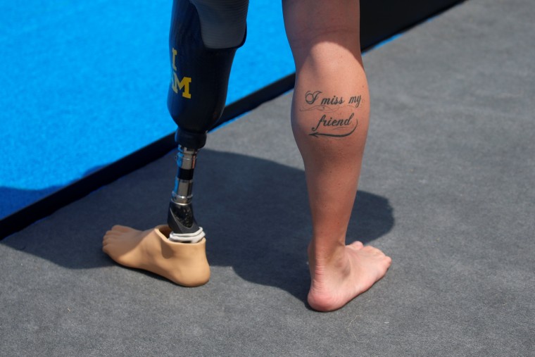Image: In reference to his lost leg, Mike Goody of Britain shows a tattoo which reads \"I miss my friend\", while standing poolside during a medal ceremony at the Invictus Games in Orlando