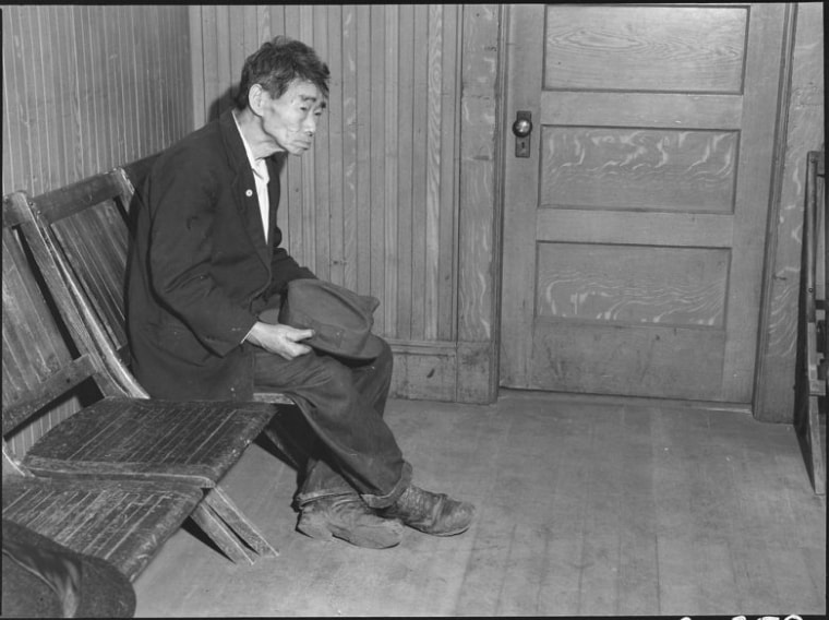 April 25, 1942, Byron, California. Original caption: Toshi Mizoguchi waiting at the Wartime Civil Control Administration station to register for evacuation. Mr. Mizoguchi came to the United States from Japan in 1892 and has been a farm laborer on California ranches since that time. He is unmarried. He is seen wearing an American flag on a celluloid button.