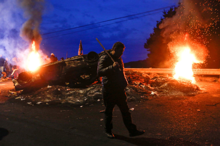 Image: A fisherman walks past a barricade blocking a road during a protest on Chiloe island, Chile