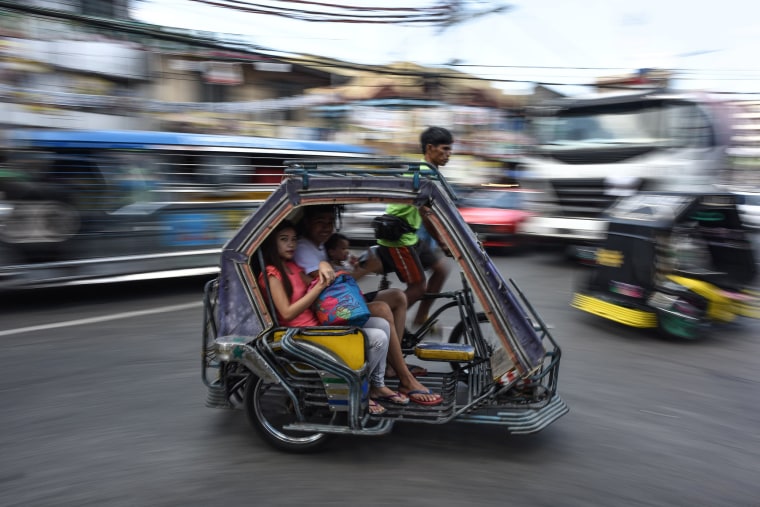 Image: A Filipino family rides in a traditional tricycle taxi ahead of the presidential and vice presidential elections in Manila