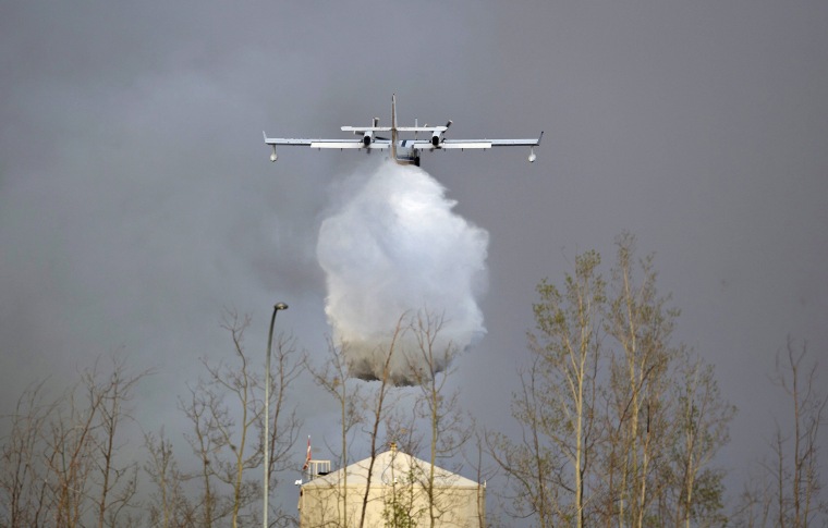 Image: A water bomber drops water on a nearby wildfire in Fort McMurray, Alberta.