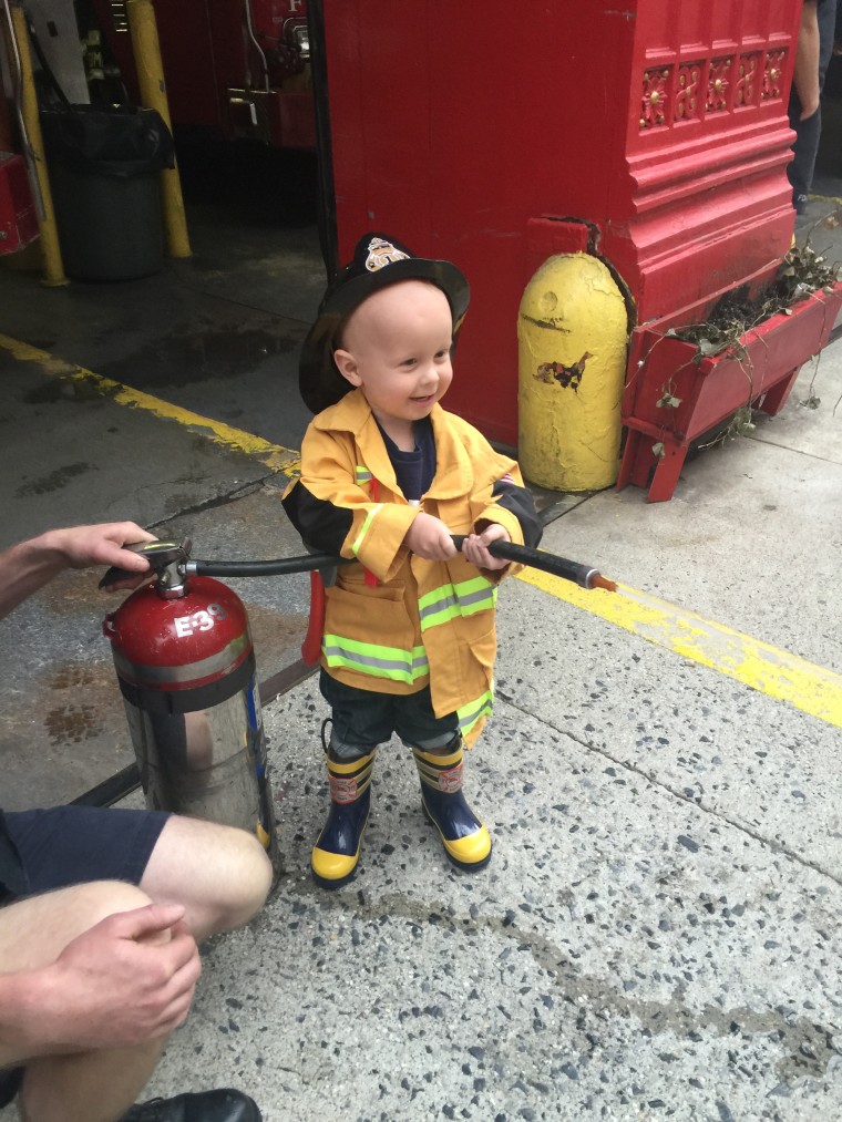 Little boy dressed as firefighter with hose