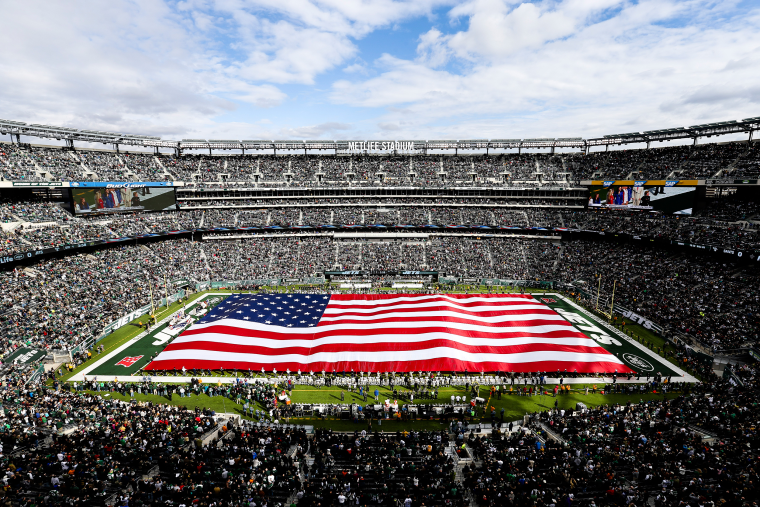Image: A giant American flag is unfurled on the field in honor of military veterans