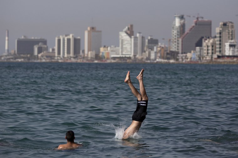 Image:  Israeli Arab youth jumps into the water in unusually warm weather at the old port of Jaffa