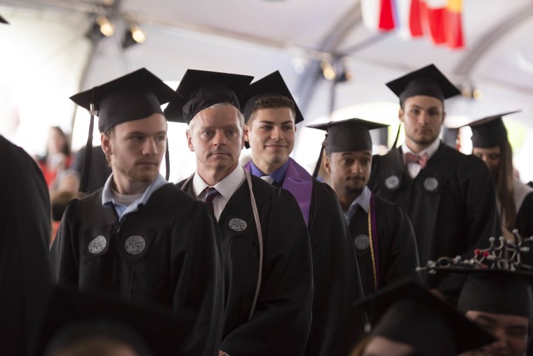 Mike Vaudreuil, second from left, stands in line to get his diploma from Worcester Polytechnic Institute on Saturday. The 54-year-old got graduated after working night shifts as a custodian at the college for eight years.