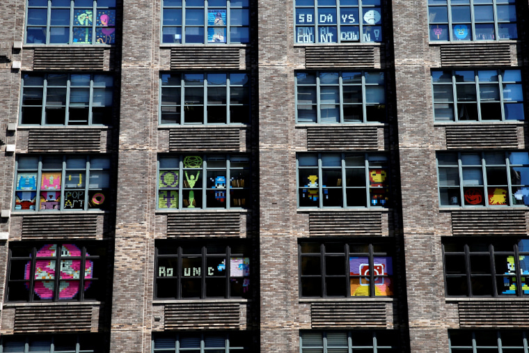 Image: Images created with Post-it notes are seen in the windows of offices at 75 Varick Street in lower Manhattan, New York during \"Post-it note war\"