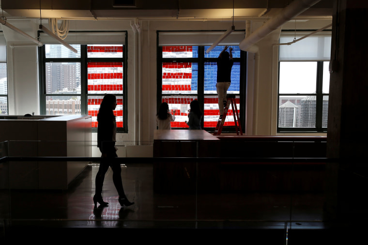 Image: Employees create U.S. flag image on a window with Post-it notes at the Horizon Media offices at 75 Varick Street in lower Manhattan, New York during \"Post-it note art war\"