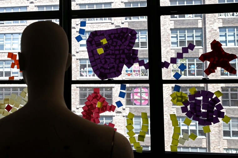 Image: A mannequin stands near images created with Post-it notes in windows at 200 Hudson street in lower Manhattan, New York during \"Post-it note art war\"