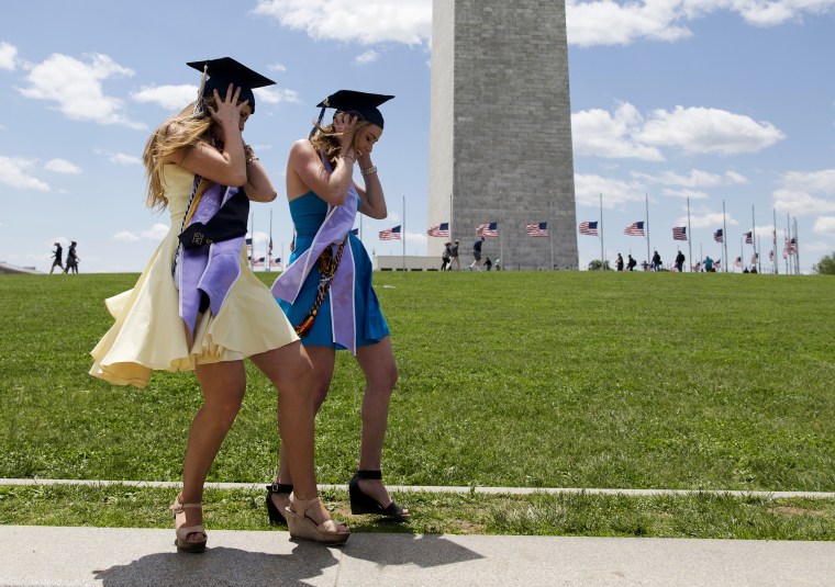 Image: Graduates struggle against a strong wind as they pose for graduation