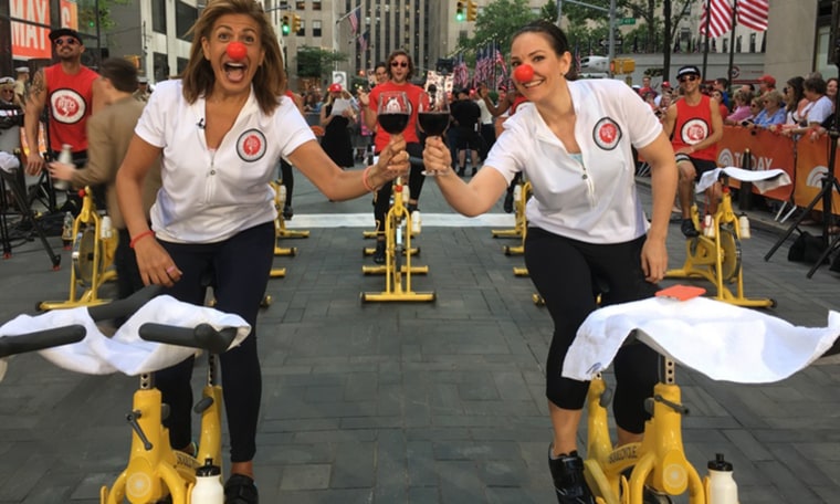 TODAY's Hoda Kotb and Erica Hill toast Red Nose Day on stationary bikes on the plaza.