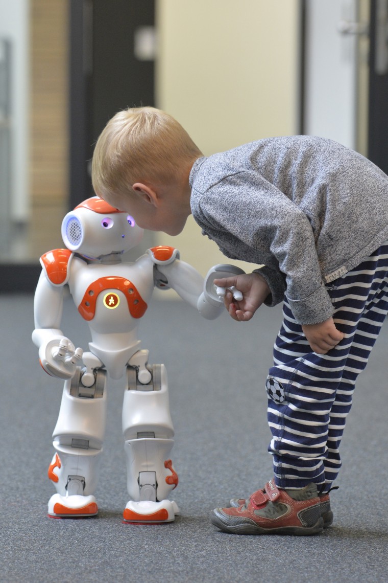 Image: A child with language robot Nao