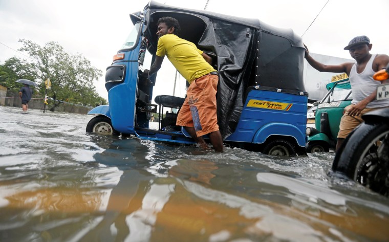 Image: A man pushes his trishaw after it got stuck on a flooded road during a wet day in Colombo