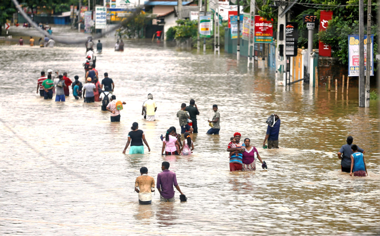 Image: People walk through a flooded road after they moved out from their houses in Biyagama