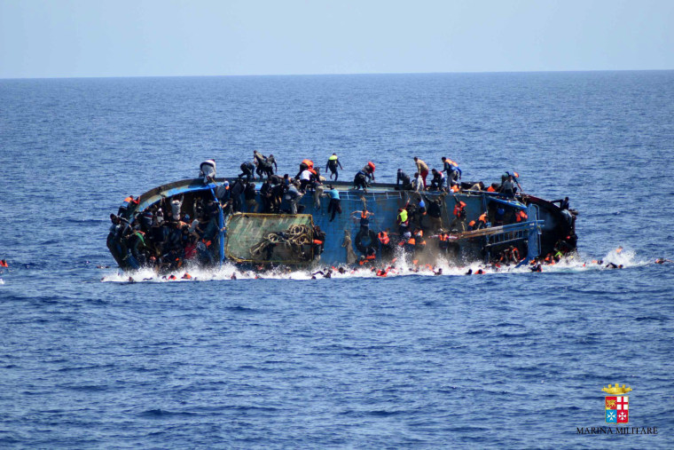Image: People jump out of a boat right before it overturns off the Libyan coast