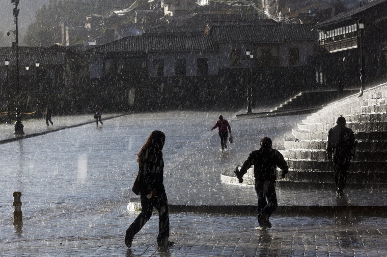 Image: People walk under a heavy rain downtown in Cusco