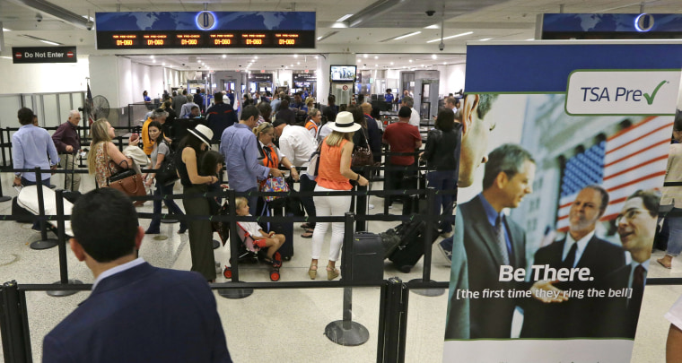 Image: Travelers stand in line as they prepare to pass through a TSA checkpoint