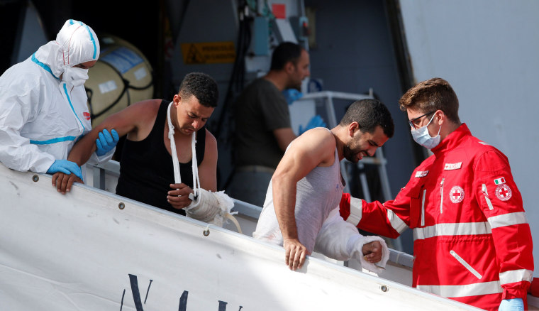 Image: Migrants are helped as they disembark from Italian navy ships \"Bettica\" in the Sicilian harbour of Porto Empedocle